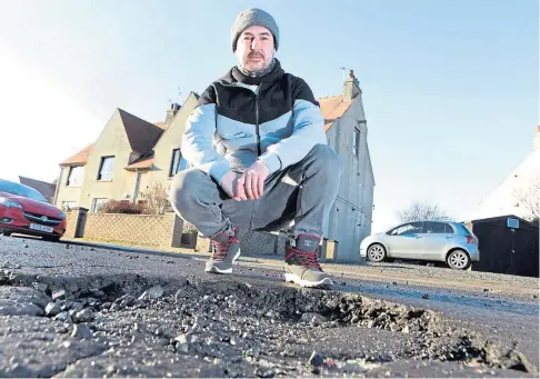  ??  ?? ROAD HOLE: Resident Lewis Heaney beside a pothole on Inverie Street, St Monans. Picture by Gareth Jennings.