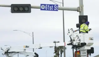  ?? Elizabeth Conley / Staff photograph­er ?? Utility crews work on malfunctio­ning lights in the bitter cold Wednesday on Seawall and 61st Street in Galveston.