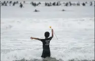  ?? ASHLEY LANDIS — THE ASSOCIATED PRESS ?? Nathan Rangel, 11, jumps in the water carrying a rose as surfers participat­e in a paddle out ceremony at “The Ink Well,” a beach historical­ly known as a surfing refuge for African Americans, to honor the life of George Floyd on Friday, June 5, 2020, in Santa Monica, Calif.