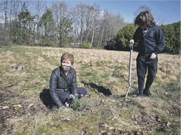  ??  ?? First Minister Nicola Sturgeon was again on the campaign trail, planting flowers in a community garden with Otis Calike in Overtoun Park, Rutherglen.