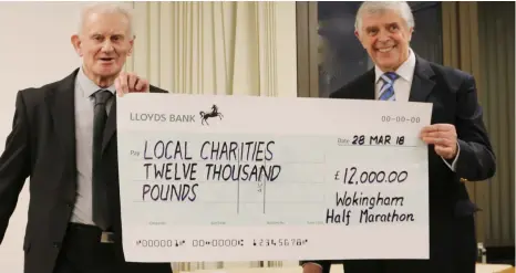  ?? Pictures: Tony Johnson ?? Brian Bacon and Peter Evans hold up a cheque showing the total amount of money donated to charity by runners in this year’s Wokingham Half Marathon