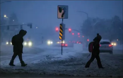  ?? FRANCISCO KJOLSETH — THE SALT LAKE TRIBUNE VIA AP ?? Commuters negotiate snow covered streets in the early hours in the Salt Lake Valley on Wednesday in Salt Lake City, Utah. Brutal winter weather hammered the northern U.S. Wednesday with “whiteout” snow, dangerous wind gusts and bitter cold, shutting down roadways, closing schools and businesses and prompting dire warnings for people to stay home.