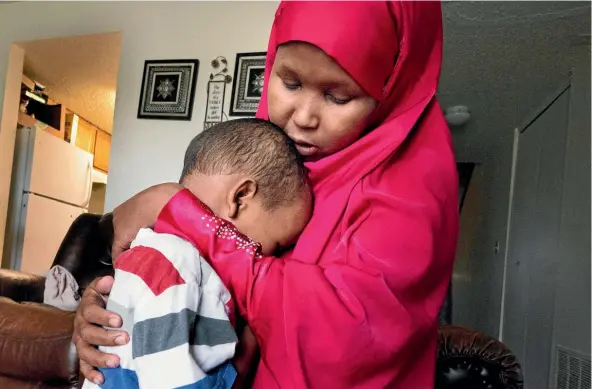  ??  ?? Suaado Salah comforts her 3-year-old son Luqman after he and his 18-month-old sister caught measles during Minnesota’s current outbreak.