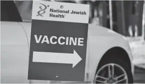  ?? DAVID ZALUBOWSKI/AP ?? A sign directs motorist to a vaccinatio­n site in east Denver. Merriam-webster has declared “vaccine” its 2021 word of the year.