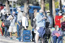  ?? OCTAVIO JONES/GETTY ?? Seniors and first responders wait in line to receive a COVID-19 vaccine at the Lakes Regional Library on Dec. 30 in Fort Myers.