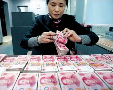  ?? AP ?? A clerk counts two years. Chinese currency notes at a bank in Huaibei, China. The Chinese yuan slid Thursday to its lowest level in almost