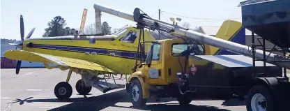  ?? Staff photo by Neil Abeles ?? The long arm of a loading truck is streaming fertilizer into the airplane’s hopper, which then disperses the fertilizer over tree plantation­s. This action is taking place at the Atlanta Municipal Airport last Sunday.