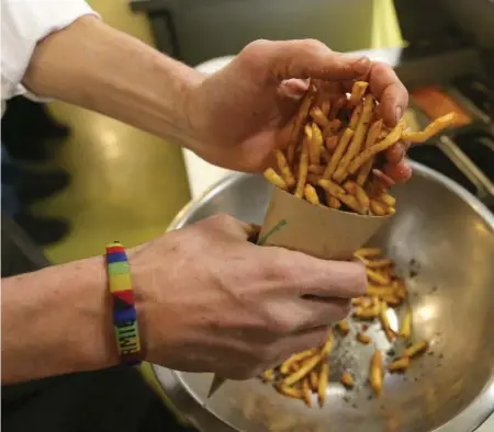  ?? VINCE TALOTTA PHOTOS/TORONTO STAR ?? Jamie Kennedy scoops his "populist" fries into a cone at Gilead Café on the restaurant’s closing day, March 31. See his recipe on L10.