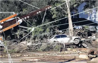  ??  ?? A damaged car sits over fallen and debris behind downed power lines in Montecito, California yesterday.