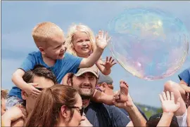  ?? AMERICAN-STATESMAN 2017 ?? Hudson Meringola and Anya Lysohir, both 3, pop bubbles while on their fathers’ shoulders during Bubblepalo­oza.