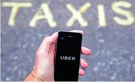  ??  ?? A photo illustrati­on shows the Uber app logo displayed on a mobile telephone, as it is held up for a posed photograph in central London. This logo has been updated and is no longer in use. (Reuters)
