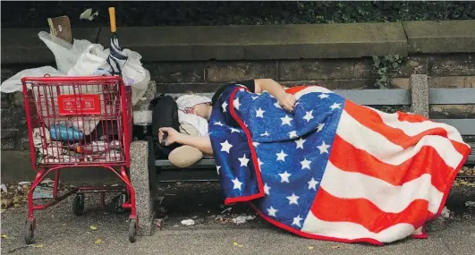  ?? SPENCER PLATT/ GETTY IMAGES ?? A homeless man sleeps on a park bench last September in New York City. According to the U. S. Census Bureau, 16 per cent of Americans live below the poverty line. A high portion of children and single mothers — 20 per cent and 33 per cent respective­ly...