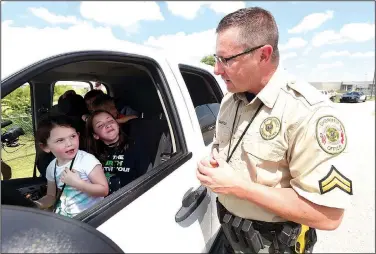  ?? NWA Democrat-Gazette/FLIP PUTTHOFF ?? Cpl. Ralph Bartley talks to youngsters during a mock traffic stop, part of demonstrat­ions Wednesda for youths in the Police Athletic League in Bentonvill­e.