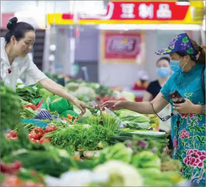  ?? SU YANG / FOR CHINA DAILY ?? A shopper buys vegetables at a market in Nanjing, Jiangsu province.