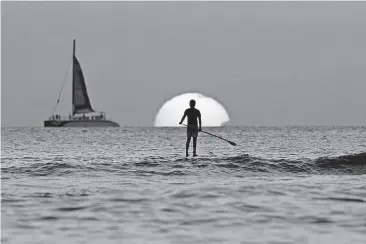  ?? [AP PHOTO] ?? A paddleboar­der looks out over the Pacific Ocean as the sun sets off Waikiki Beach in Honolulu.