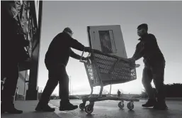  ?? CHARLIE RIEDEL/AP ?? People transport a television on Black Friday in Overland Park, Kansas. Lower-income shoppers say they are scaling back gift-giving in 2021 because of inflation.