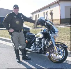  ?? STAFF PHOTO BY ANDREW CEPHAS ?? Cpl. Kris Syvertsen of the Charles County Sheriff’s Office’s Traffic Operation Unit in the Special Operations Division stands beside his marked patrol motorcycle. Beside his leg is a sticker in memory of Sgt. Timothy Minor who died Feb. 12, 1996, after...