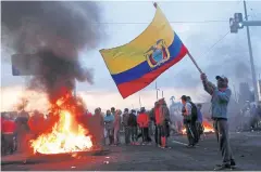  ?? REUTERS ?? A man waves an Ecuadorean flag next to people blocking a road during protests in Lasso, Ecuador on Sunday.