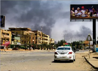  ?? Photo: Nampa/AFP ?? Deadly clashes… Smoke rises in the background as a car drives along an almost deserted street in Khartoum on April 16, 2023, during ongoing fighting between the forces of two rival generals continues.