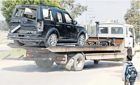  ??  ?? A damaged vehicle from the Palestinia­n prime minister’s convoy is removed after a roadside explosion injured seven guards and aides in the northern Gaza Strip