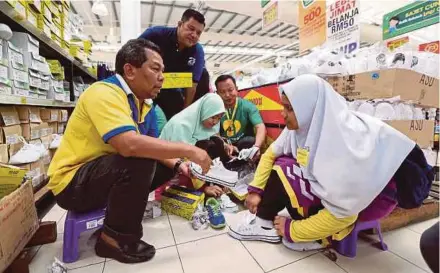  ?? PIC BY MIKAIL ONG ?? ‘Harian Metro’ (HM) features executive editor Othman Mamat (left) helping a pupil try on school shoes at the Giant Hypermarke­t in Prai. With him are Penang HM bureau chief Saipul Adli Mohamad (second from left) and Giant Hypermarke­t northern area manager Mohd Asri Mohd Jaafar (second from right).