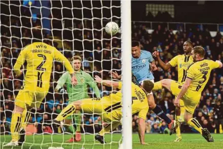  ?? AFP PIC ?? Manchester City’s Gabriel Jesus (centre) heads the ball to score against Burton Albion in a League Cup semi-final first leg match at the Etihad Stadium on Wednesday.