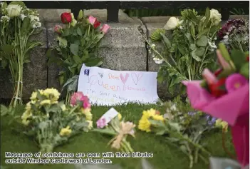  ??  ?? Messages of condolence are seen with floral tributes outside Windsor Castle west of London.