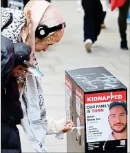  ?? ?? ROAD RAGE: Protesters caused some stores to close in Central London. Above: A woman peels off posters of Israeli hostages held in Gaza
