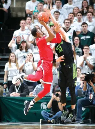  ?? Al Goldis/Associated Press ?? ■ Ohio State's Luther Muhammad, left, shoots against Michigan State's Kyle Ahrens (0) during the second half of an NCAA basketball game on Sunday in East Lansing, Mich. Michigan State won 62-44.