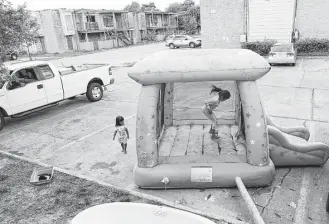  ?? Elizabeth Conley photos / Houston Chronicle file ?? Monica Cruz jumps in an inflatable bouncy house in the parking lot at Rockport Apartments. Some tenants are making their own repairs to their apartments flooded by Hurricane Harvey.