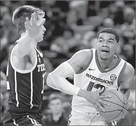  ?? Arkansas Democrat-Gazette/CHARLIE KAIJO ?? Arkansas guard Mason Jones (right) drives to the basket against a Texas A&amp;M defender Saturday during the Razorbacks’ 87-80 loss to the Aggies at Walton Arena in Fayettevil­le.