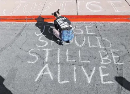  ?? K.M. Cannon Las Vegas Review-journal @Kmcannonph­oto ?? Jazz Appin writes messages in chalk Friday outside the Clark County Government Center while a public review of evidence was underway inside the center on the deadly police shooting of Black Lives Matter protester Jorge Gomez.