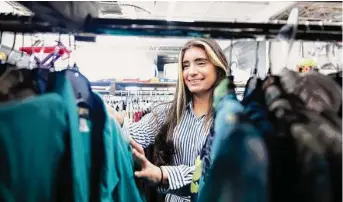  ?? Khadejeh Nikouyeh/Associated Press ?? Paola Garcia skims through items of clothing on Aug. 31 at The WearHouse in Charlotte, N.C. The uptick in the secondhand market has been attributed to rising prices across the board.