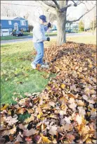  ?? File photo ?? A man rakes leaves in front of his house.