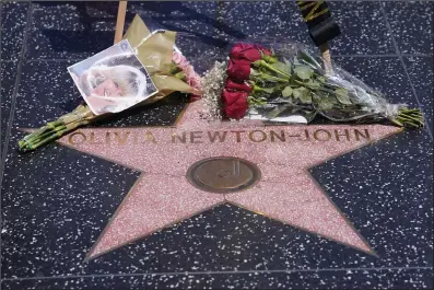  ?? AP PHOTO DAMIAN DOVARGANES ?? Flowers adorn Olivia Newton-John’s Hollywood Walk of Fame star in Los Angeles, Monday. Newton-John, the Grammy-winning superstar who reigned on pop, country, adult contempora­ry and dance charts with such hits as “Physical” and “You’re the One That I Want” has died. She was 73.