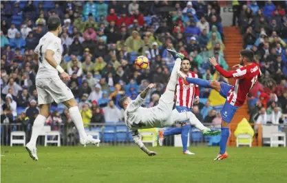  ??  ?? MADRID: Real Madrid’s Sergio Ramos, centre, attempts an over heard kick next to Sporting’s Carlos Carmona, right, during a Spanish La Liga soccer match between Real Madrid and Sporting at the Santiago Bernabeu stadium in Madrid, yesterday. Real Madrid...
