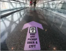  ?? AP PHOTO/MICHAEL DWYER ?? In this Nov. 20 file photo, travelers walk across a nearly empty skyway bridge towards the Uber and Lyft shared ride pick-up point at Logan Airport in Boston. Fresh off of their initial public offerings the year before and still struggling to show they can be profitable, the ride-hailing services were clobbered by the pandemic in 2020, as people stopped taking cars and huddled down at home. In May, Uber laid off 3,700 people, or about 14% of its workforce. Lyft also announced job cuts.