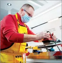  ?? CHEN ZHONGHAO / XINHUA ?? A worker polishes a snowboard in a China-made waxer vehicle during the Beijing Winter Olympics.