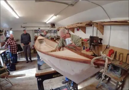  ?? JONATHAN TRESSLER — THE NEWS-HERALD ?? From left, background, Jim Batteiger, Cleveland Amateur Boatbuildi­ng and Boatbuildi­ng Society President Ed Neal and Mentor resident Jim Jackson look on Dec. 19 as Lakewood resident Wes Roepke, foreground, preps the group’s Six-Hour Canoe with...