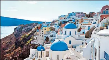  ?? TRISH FEASTER/RICK STEVES’ EUROPE ?? The picturesqu­e village of Oia on Santorini, built atop a volcanic crater, is awash in white and blue.