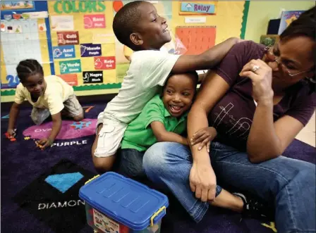  ?? MIKE BROWN/THE COMMERCIAL APPEAL ?? Prekinderg­arten teacher Lucenda Edwards (right) laughs as she is playfully mobbed by students Derrick Miller (left), 5, and Derrius Johnson (center), 4, during class at the Ernestine Rivers Center on Mississipp­i Boulevard in South Memphis.