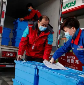  ?? PHOTO: REUTERS ?? Stockpilin­g: Workers unload groceries at a Beijing petrol station where customers can buy supplies while they refuel as China is hit by an outbreak of the coronaviru­s.