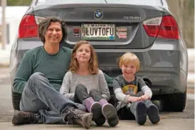  ?? AP PHOTO/ROBERT F. BUKATY ?? Peter Starosteck­i and his kids, Sadie, center, and Jo Jo, pose Wednesday behind their car with the vanity license plate that the state of Maine has deemed inappropri­ate, in Poland, Maine.