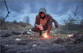  ?? Kiran Ridley / Getty Images ?? A refugee lights a fire to keep warm at daybreak on Friday in Dunkirk, France. At least 27 people, including five women and a young girl, died Wednesday trying to cross the Channel to the U.K. in an inflatable dinghy in an incident that the Internatio­nal Organisati­on for Migration described as the biggest single loss of life in the Channel since it began collecting data in 2014. There are currently 1,800 migrants and refugees living in northern France.