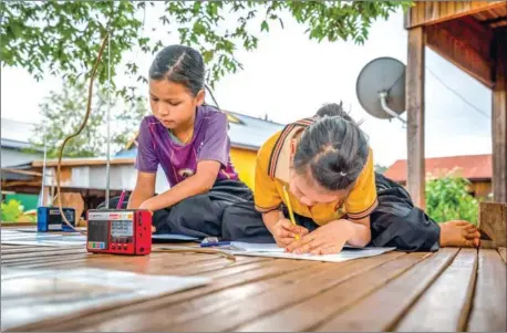  ?? UNICEF CAMBODIA/ANTOINE RAAB ?? Children study around the radio which provides educationa­l support during the closure of their school amid the Covid-19 pandemic in Paor Kekchong village, in Rattanakki­ri province’s Borkeo district.