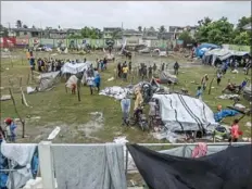  ?? Reginald Louissant Jr./AFP via Getty Images ?? People make repairs and create shelter Tuesday after spending the night outside in the aftermath of an earthquake, while facing the severe inclement weather of Tropical Storm Grace, near Les Cayes, Haiti. The massive 7.2-magnitude earthquake killed nearly 2,000 people and toppled thousands of buildings Saturday.