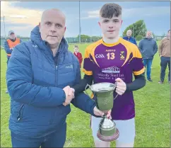  ?? ?? Kieran Kelleher, St Catherine’s Minor Captain receiving the U18 Div 2 football trophy from Martin Leahy, Rebel Óg following the recent final against Mayfield.