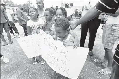  ?? ASSOCIATED PRESS ?? Children hold signs reading “Black Lives Matter” outside the Triple S convenienc­e store July 6 in Baton Rouge, La. Alton Sterling was shot and killed the previous day by Baton Rouge police outside the store where he was selling CDs. The U.S. Justice...