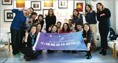  ?? ?? Ma (first left, kneeling) organizes a training session designed to help community social workers maintain their mental health while working as caregivers.