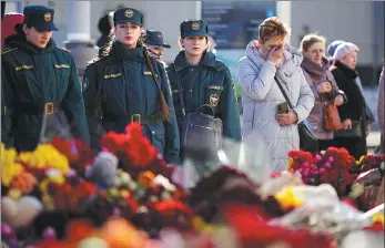 ?? ALEXANDER ZEMLIANICH­ENKO/AP ?? People stand at a makeshift memorial in front of the Crocus City Hall on the outskirts of Moscow on Wednesday.